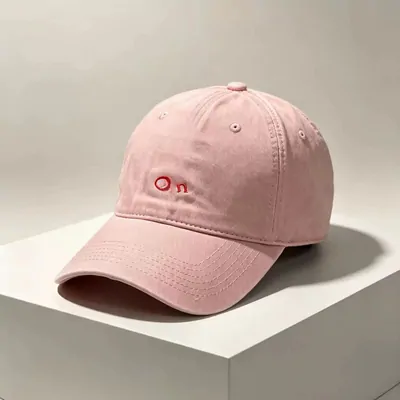 A pink cotton baseball cap on a white plinth